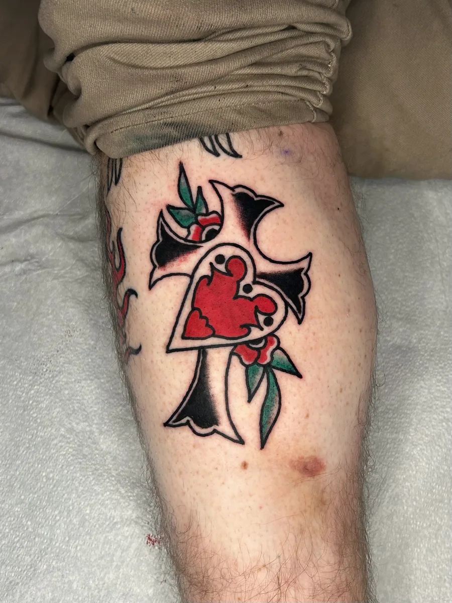Traditional cross with a red heart and roses tattooed on a calf by Joel at True North Tattoo in Lancaster, PA