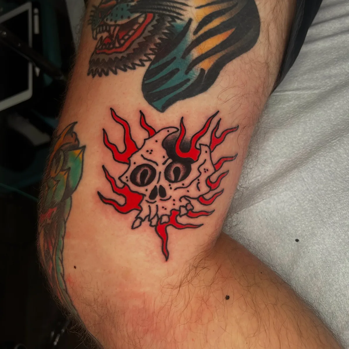 Traditional flaming skull tattoo in red and black on an inner arm by Joel at True North Tattoo in Lancaster, PA