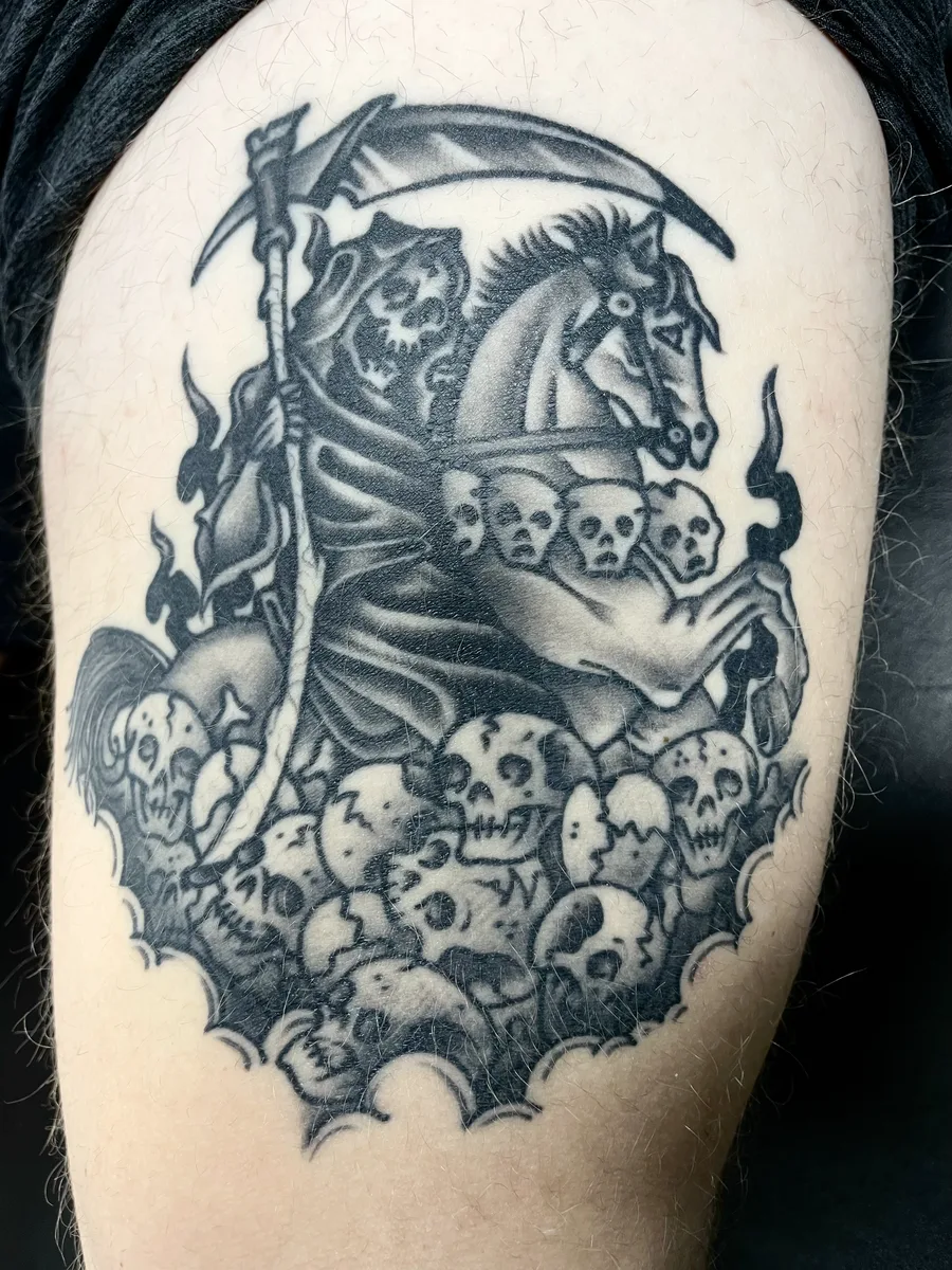 Black and grey reaper on horseback over a pile of skulls, tattooed on an upper arm by Josh Espenschied at True North Tattoo in Lancaster, PA