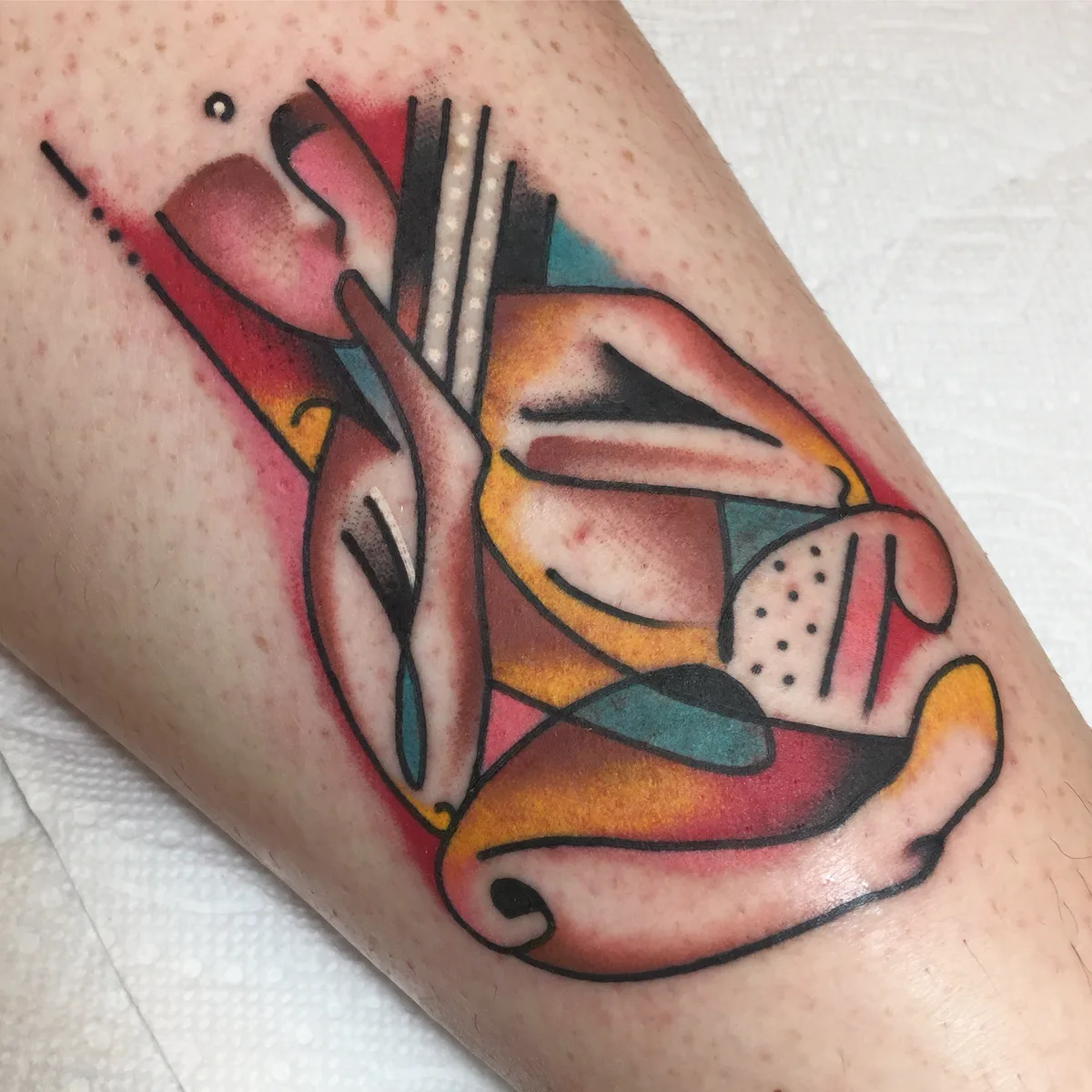 Abstract neo traditional swallow tattoo in pink, yellow and teal on a lower leg by Josh Espenschied at True North Tattoo in Lancaster, PA