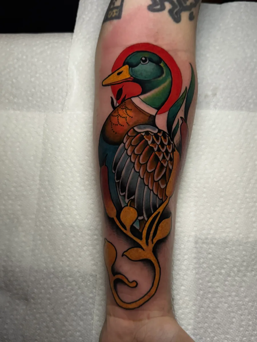 Neo traditional mallard duck forearm tattoo in green, brown and gold with a red halo by Reed Drury at True North Tattoo in Lancaster, PA